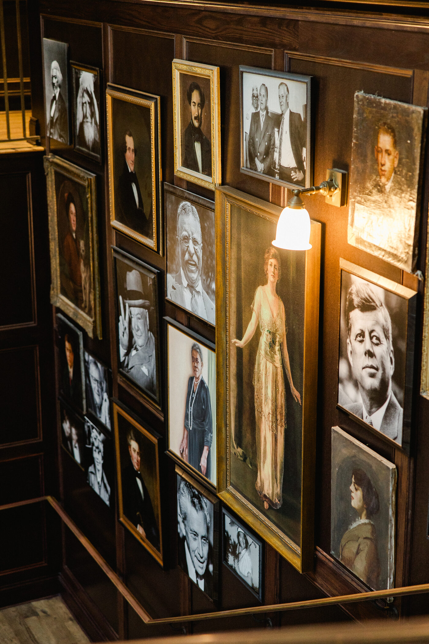 Vintage portrait gallery wall lit by warm wall sconces inside the Oxford Exchange in Tampa — Tampa Bay wedding photographer Ailyn La Torre