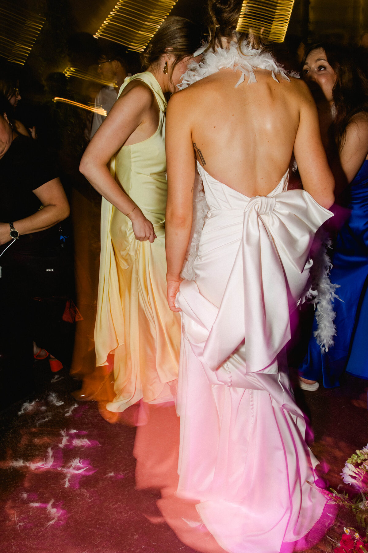 Bride in a backless gown with a statement bow dancing under vivid pink lights at a destination wedding reception — luxury wedding photographer Ailyn La Torre