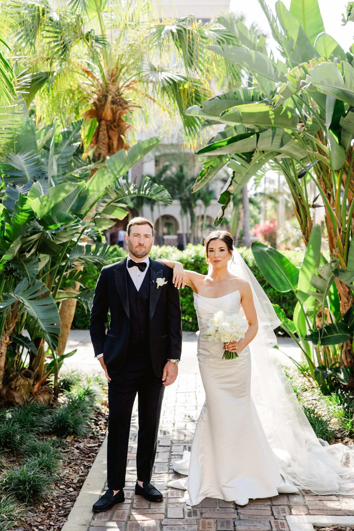 Couple standing together in the lush tropical garden courtyard at the Vinoy in St. Petersburg — luxury wedding photographer Ailyn La Torre